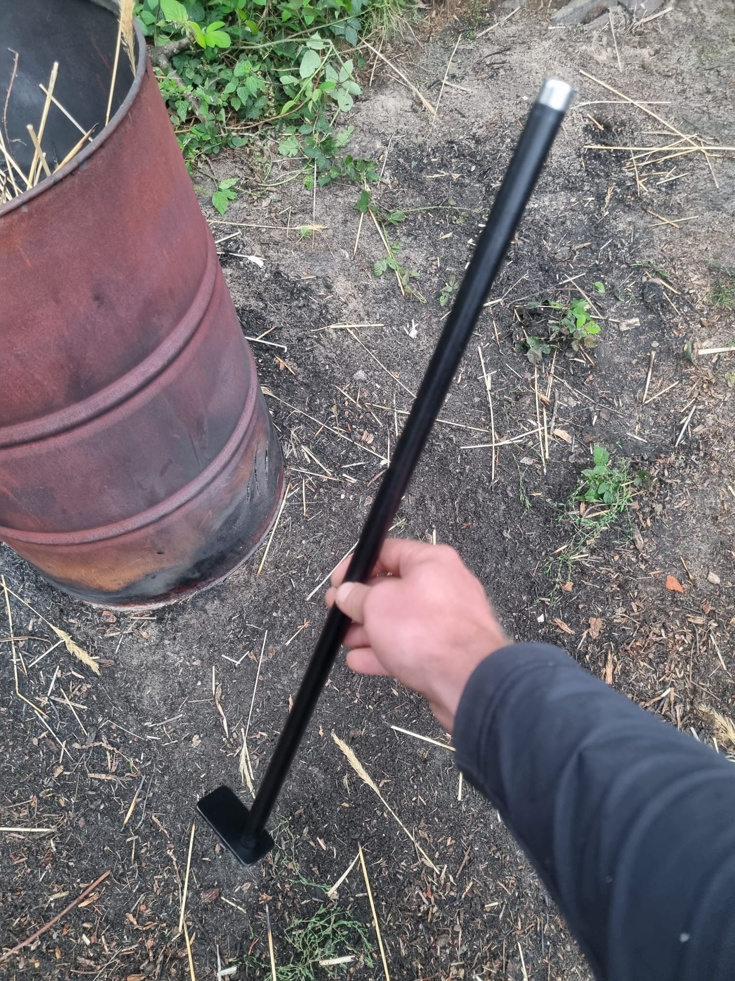 Flamman pook en blaaspijp in gebruik bij buitenvuur, robuust haardgereedschap met Scandinavisch design.